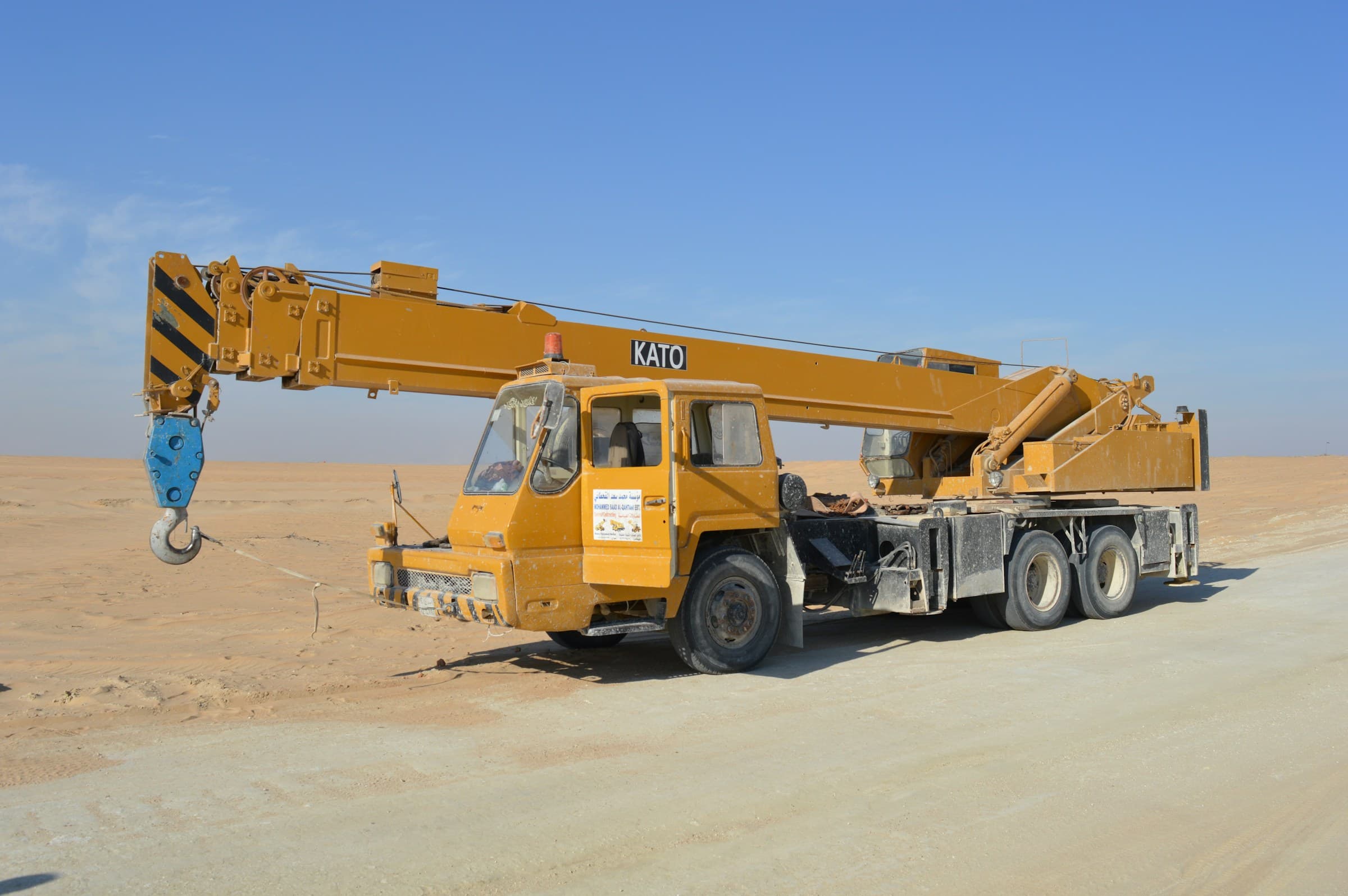 Tower crane lifting heavy steel section against a clear blue sky