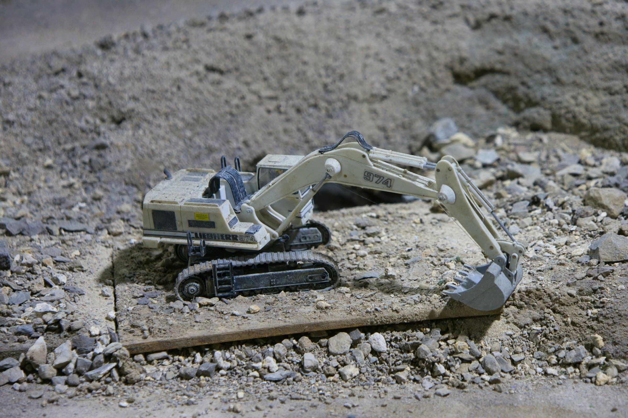 A toy excavator digging through a pile of rubble